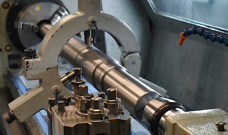 A shaft being turned on a flat bed lathe